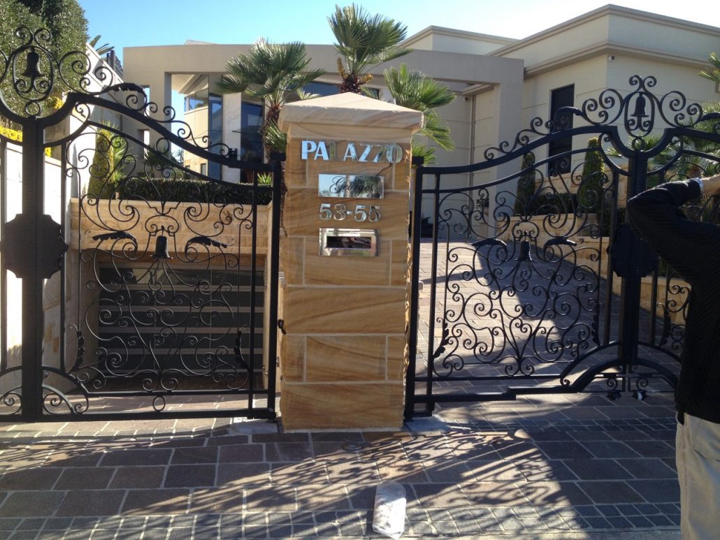 Sandstone gate pier beside wrought-iron gates