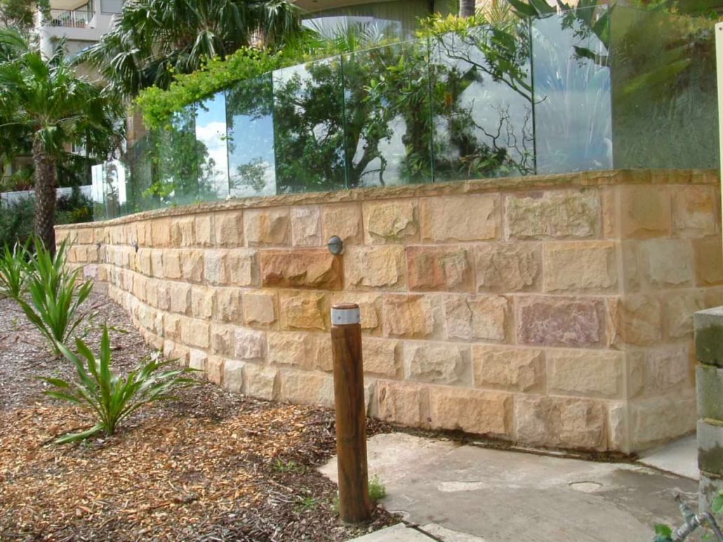 Sandstone retaining wall with a garden bed and glass balustrade